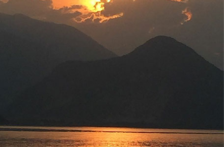 Bild Sonnenuntergang spiegelt sich im Wasser vor Bergen